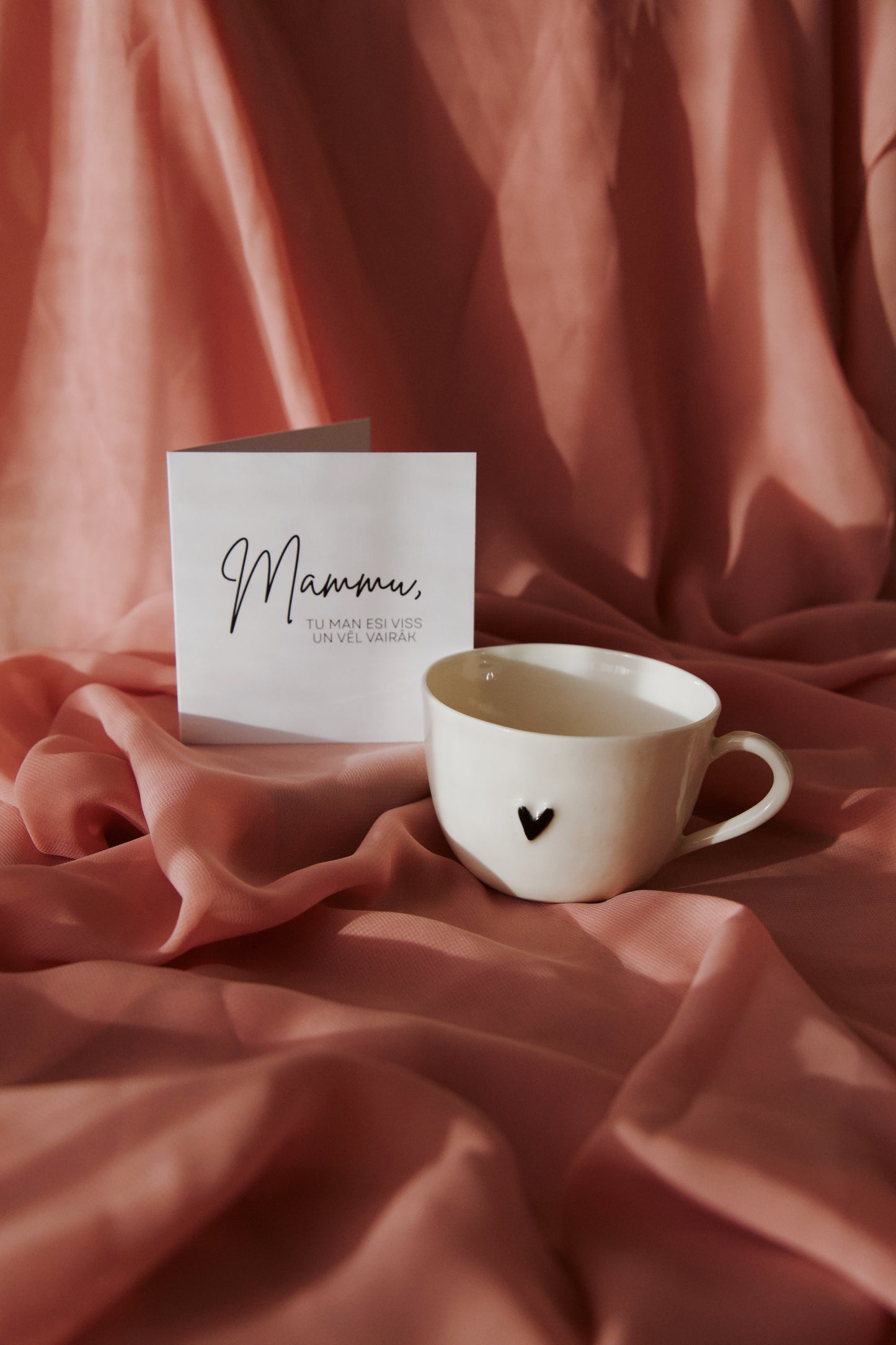 Porcelāna krūzīte ar melnu sirsniņu un apsveikuma kartīti